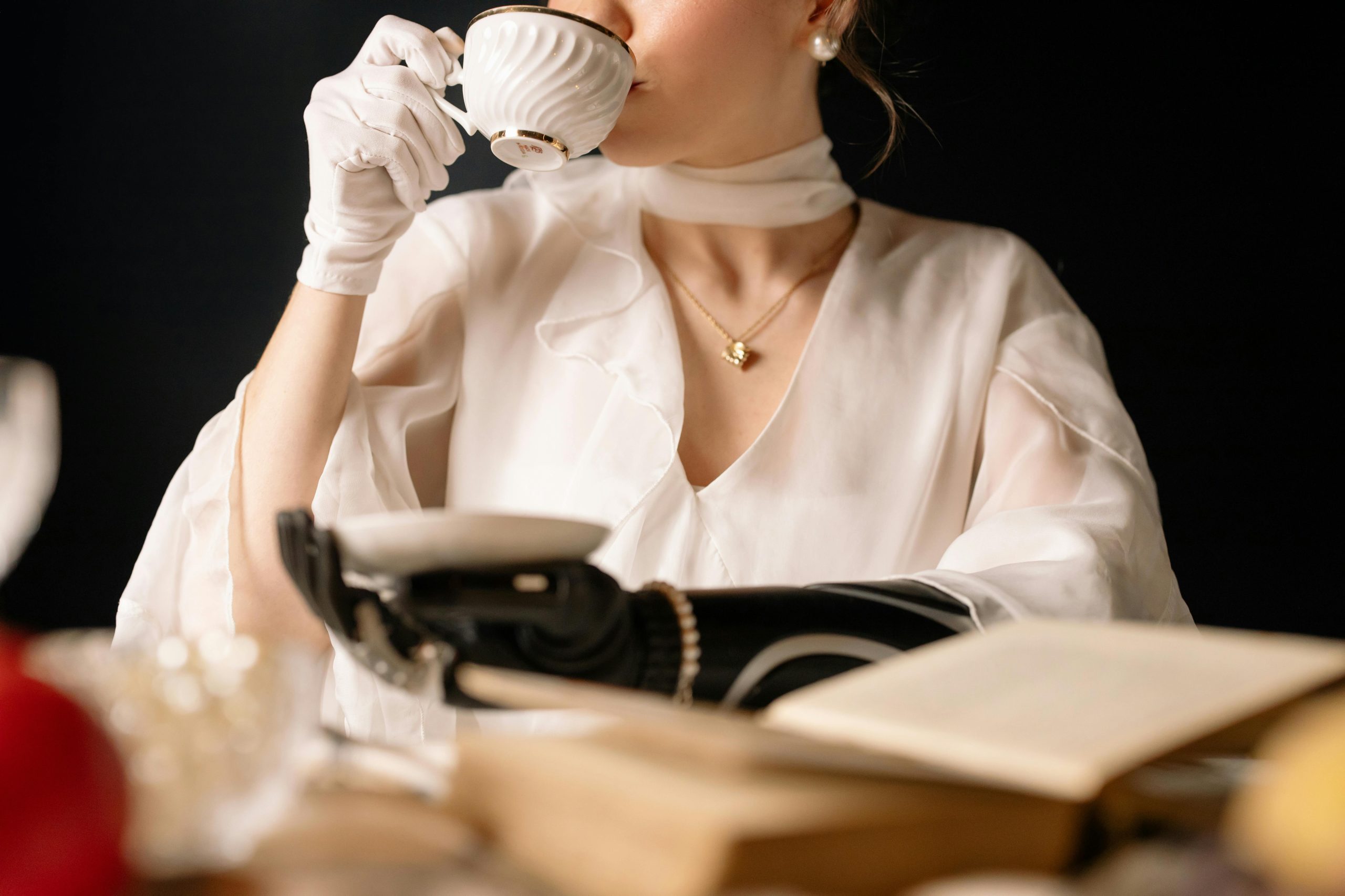 Sophisticated woman with a prosthetic arm enjoys tea, showcasing elegance and technology.